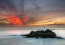 The sun sets over Godrevy lighthouse from Godrevy Head