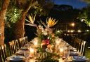 A summer tablescape at dusk with twinkling lights and a centrepiece bouquet of exotic and English blooms.