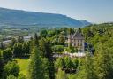 The Château de Candie is a 14th century castle with ivy-covered walls with a lush forest backdrop.