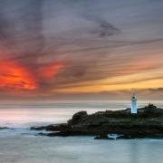 The sun sets over Godrevy lighthouse from Godrevy Head