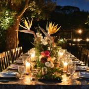 A summer tablescape at dusk with twinkling lights and a centrepiece bouquet of exotic and English blooms.