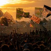 Flags wave and crowds sing along and dance on shoulders watching Fred Again on the Other Stage as the sun sets over the Glastonbury Festival at Worthy Farm in Somerset