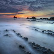 Waves break into rock pools at Welcombe Beach